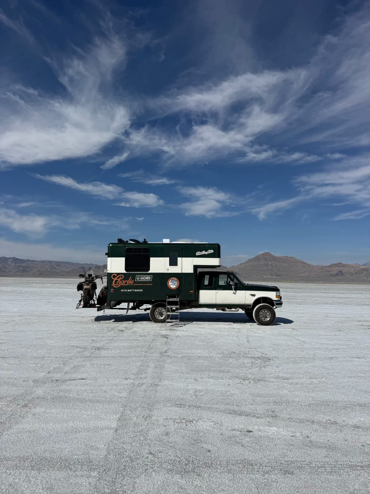 Charlie parked on a wide salt flat beneath a blue sky